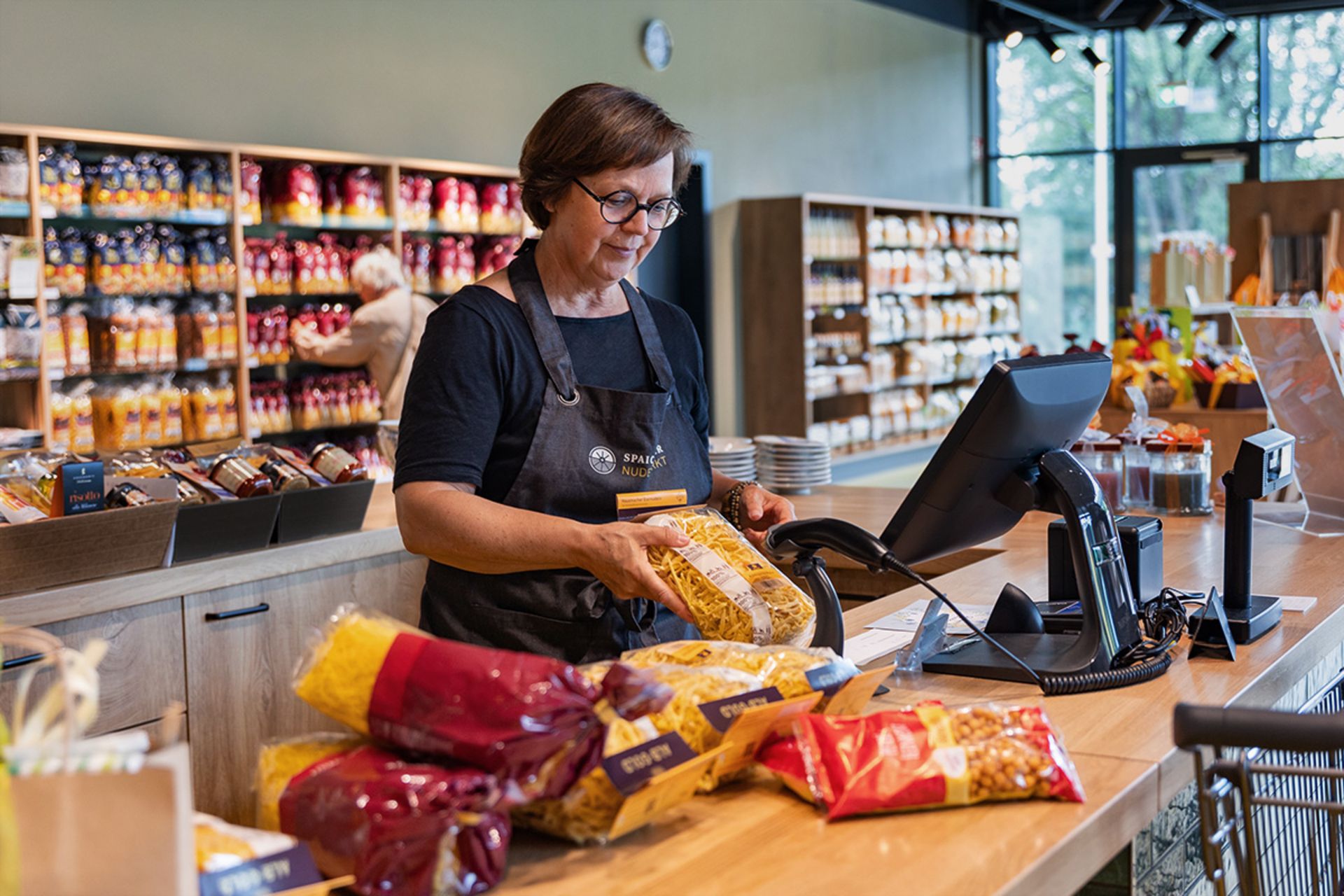 Verkäuferin scannt und verpackt Lebensmittel an der Kasse eines Supermarkts