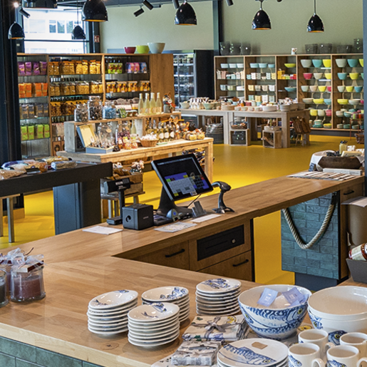 Interior view of a modern grocery store with wooden tables, shelves full of products and a cash register with a screen