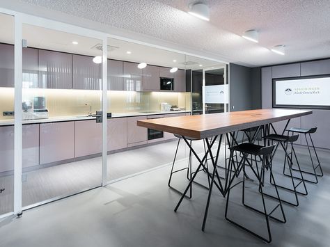 Moderne Küche mit langem Holztisch und schwarzen Barhockern, helle Schränke und eingebauter Beleuchtung
