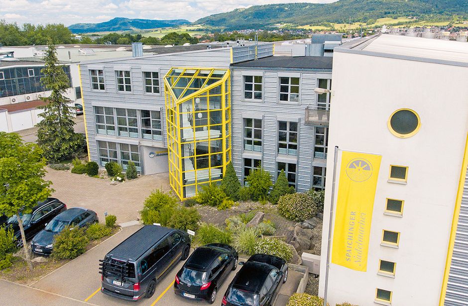 Office building with yellow accents, several parking lots and parked cars in the foreground