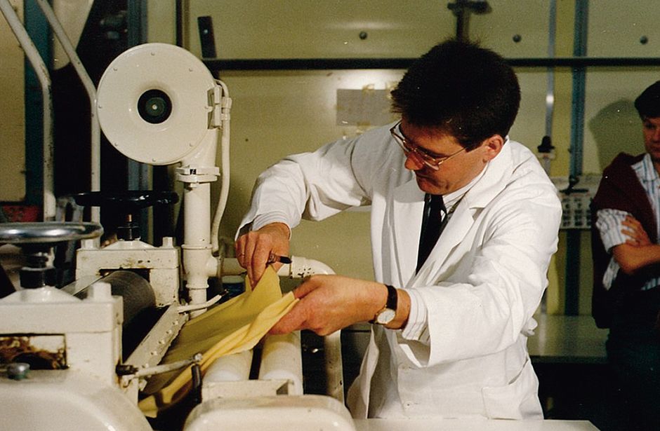 Man in white coat operates machine for making pasta dough in a production environment