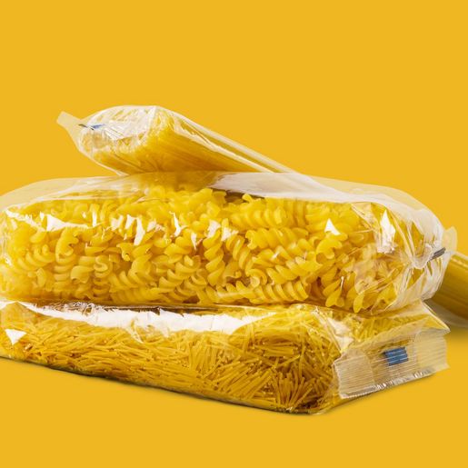 Three neutrally wrapped pasta packs against a yellow background