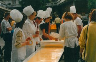 Several people in chef's clothing roll pasta dough on a long table in a world record attempt