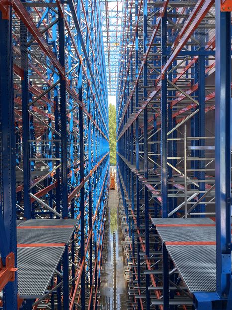 Interior view of a fully automated high-bay warehouse with high racks and automated conveyor systems
