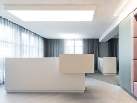 Moderner Empfangsbereich mit weißem Empfangstresen, großen Fenstern und minimalistischer Einrichtung