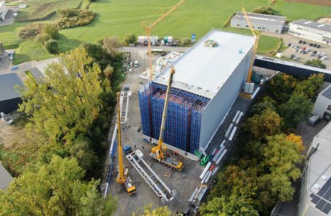 Bird's-eye view of the construction of a fully automated high-bay warehouse with cranes and building materials on an industrial site